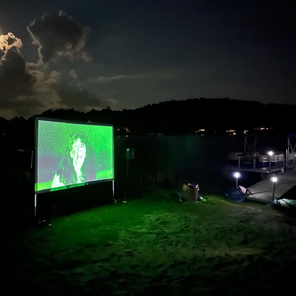 Sleepaway Camp playing on an outdoor screen by the lake at night