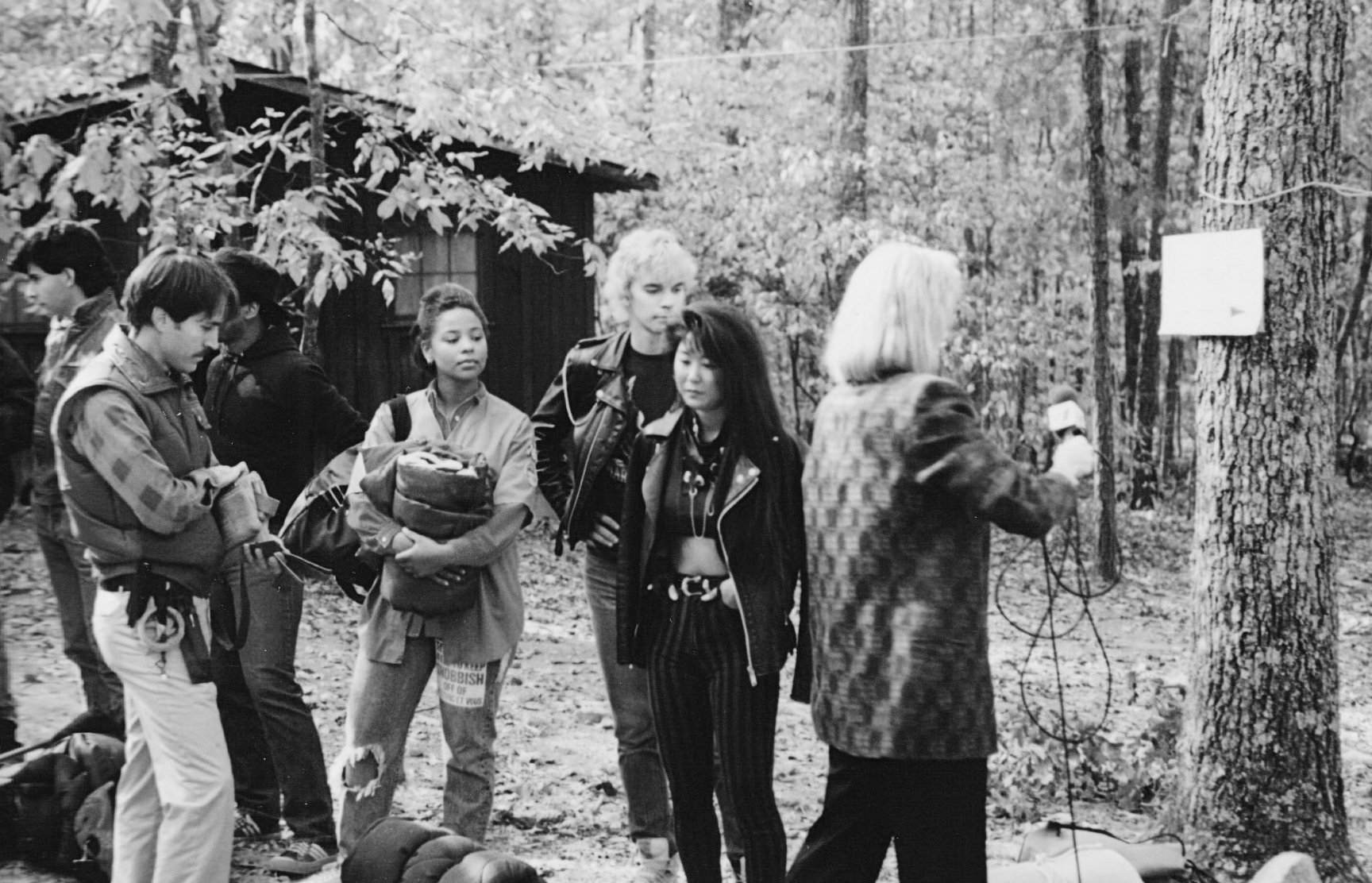 Cast and crew gathered in the woods beside lighting gear on the Sleepaway Camp III set