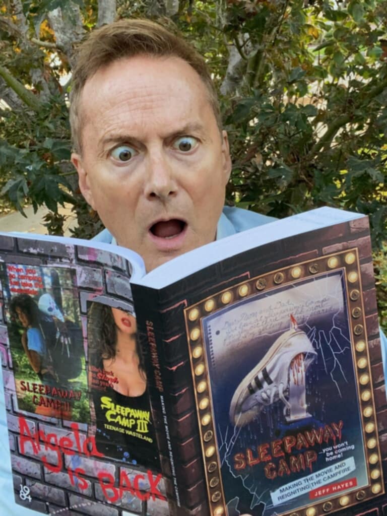 A man reads the Sleepaway Camp book with a wide-eyed, open-mouthed expression.